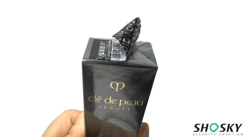 Shosky security label being peeled off a product, revealing a void pattern.