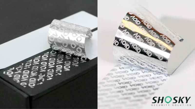 Close-up of two silver warranty void labels, one partially adhered to a black surface revealing the word "VOID" repeatedly, and another peeled back showing the adhesive side with the same "VOID" pattern