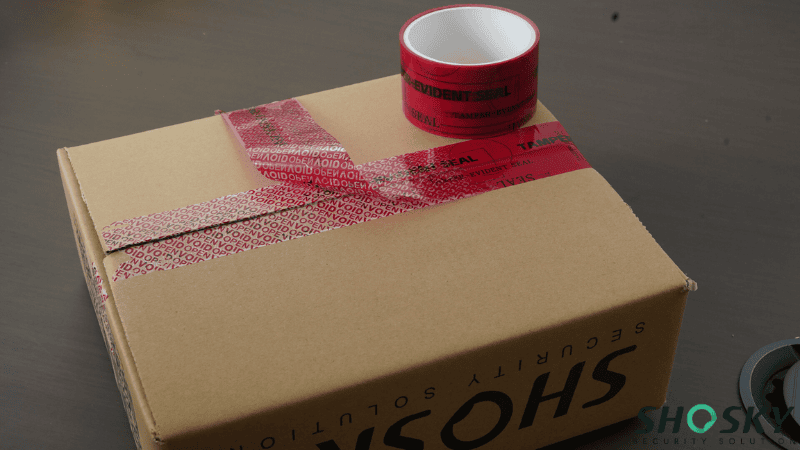 Red tamper-evident void tape on a SHOSKY security box revealing "VOID OPEN" message