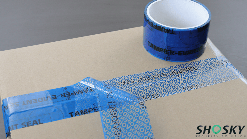 Blue tamper-evident void tape on a box revealing "VOID OPEN" message when peeled.
