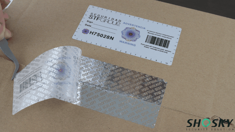 Silver holographic VOID security label showing tamper evidence on a shipping box for Phygital Asset Protection