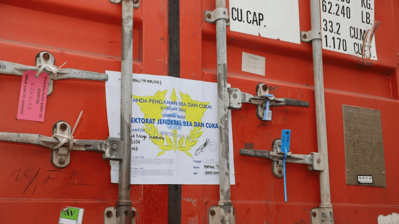 Red shipping container doors secured with customs seals, blue security tags, and official Indonesian customs documents