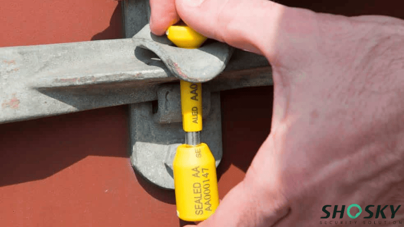 Hands applying a yellow high-security bolt seal for Bullion Logistics Security on a cargo container door.