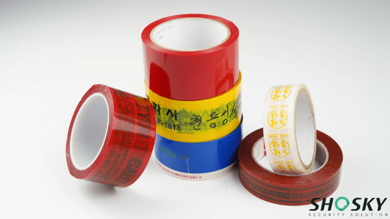 A collection of various Extreme Temperature Security Tape rolls in red, yellow, blue, and brown with custom branding and security text.