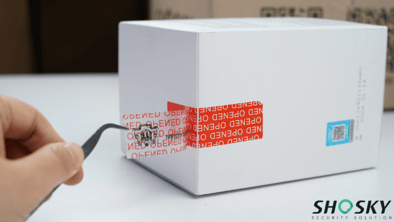 a red tamper-evident label is peeled off from a white box, revealing a hidden "OPENED" pattern for Return Fraud Prevention.