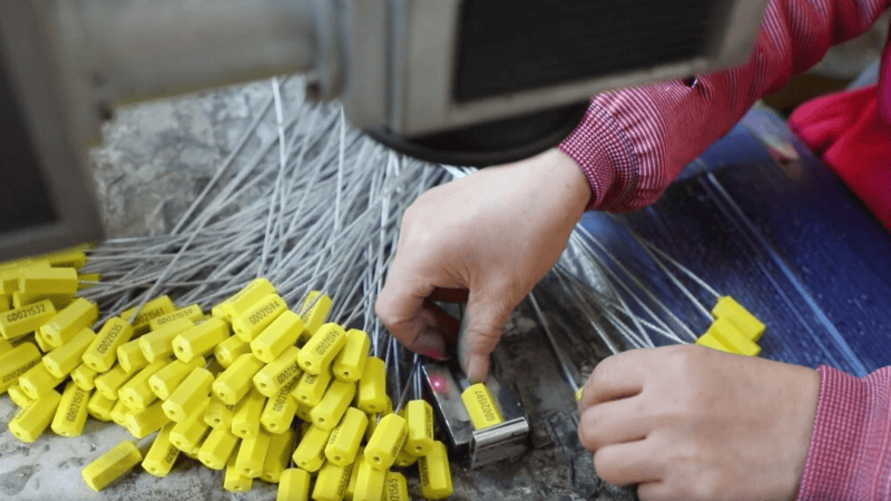 A worker manufacturing or inspecting high-security yellow cable seals with printed serial numbers, which serve as modern lead seal alternatives.