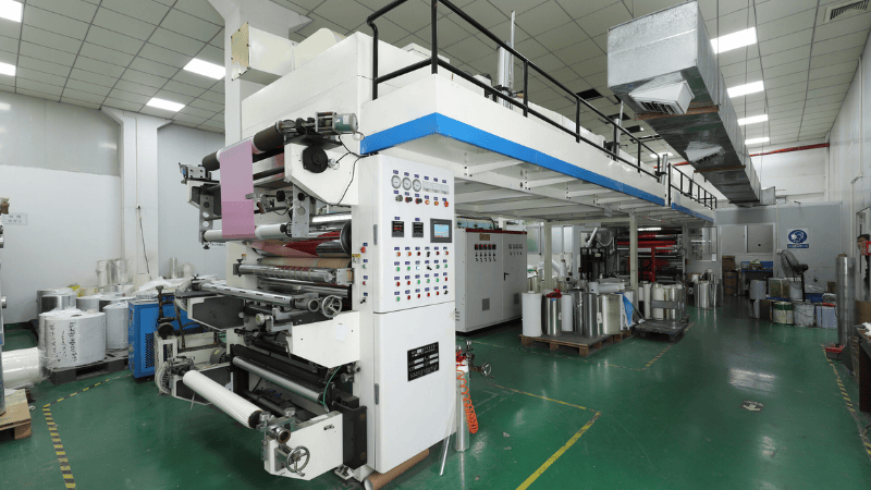 Large industrial printing and coating machine operating in the Shosky factory workshop for security tape and label production.