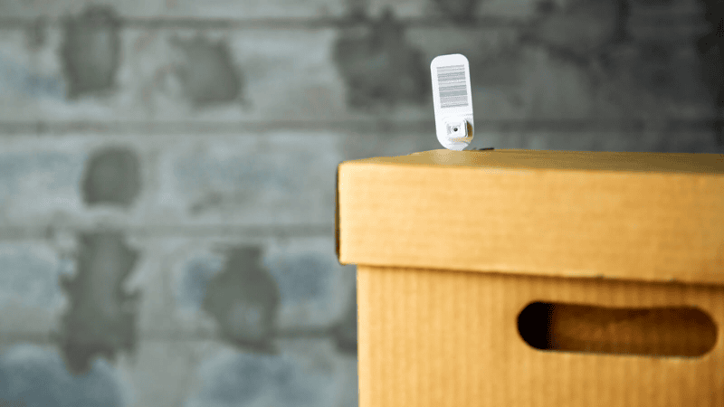 White fixed-length plastic security seal with a barcode secured to a cardboard storage box for tamper-evident protection.