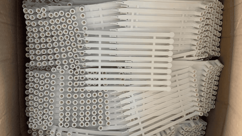 A large quantity of white fixed-length plastic security seals neatly organized and packed in mats inside a cardboard box.