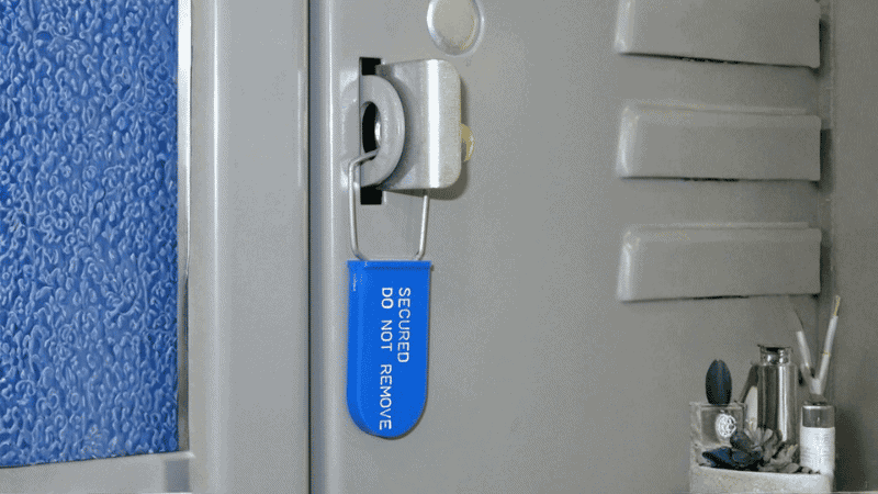 A blue plastic padlock seal printed with "SECURED DO NOT REMOVE" attached to a metal locker latch