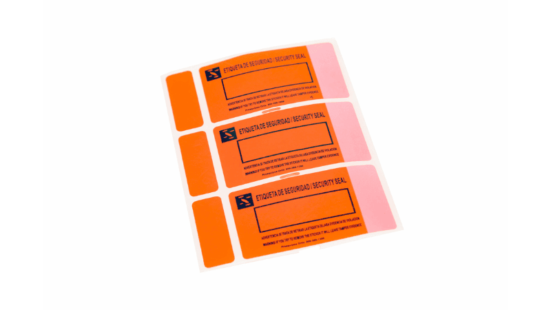 A sheet of bright orange tamper proof sticker labels printed with bilingual security warnings ("ETIQUETA DE SEGURIDAD / SECURITY SEAL") and write-on fields.