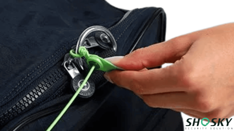 Someone securing a green plastic bag seal through the zippers of a dark blue bag for tamper protection.