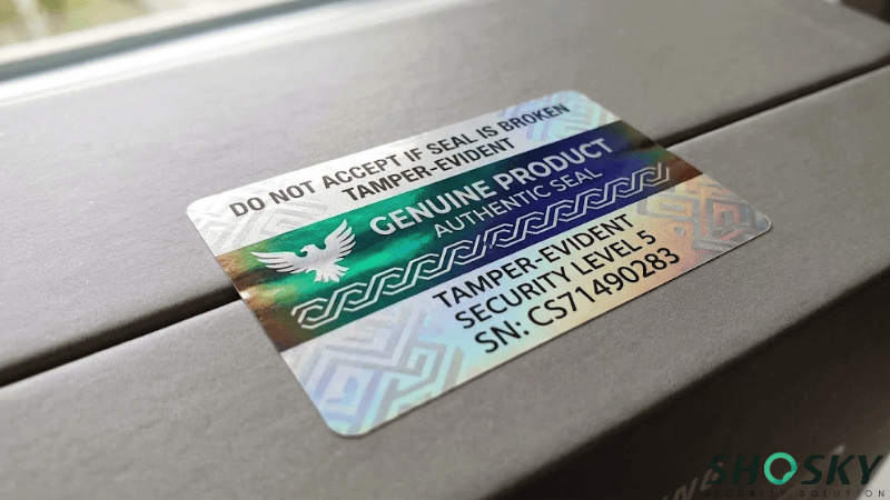 High-security optical hologram label featuring color-shifting ink, authentic product seal text, and serial number applied on a cardboard box.