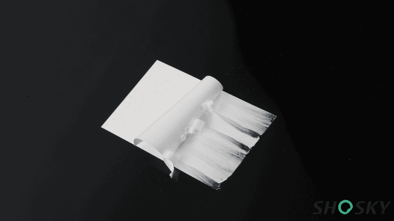Tamper-evident white Foamtac label peeling apart and splitting into fibrous layers to show anti-tamper destruction